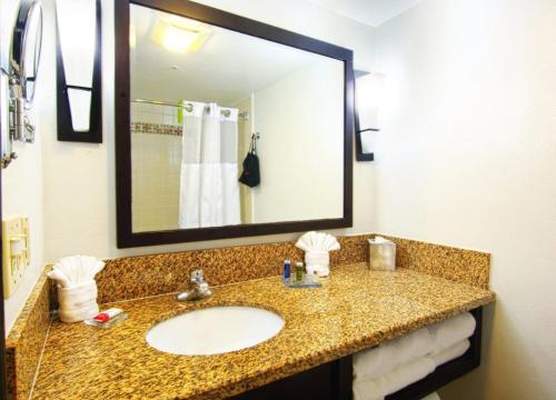 a bathroom with a sink and a mirror at Buena Park Grand Hotel & Suites in Buena Park