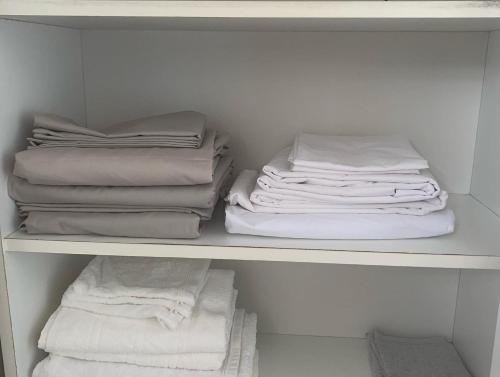 um armário com toalhas brancas numa prateleira em The N’house em Kourou