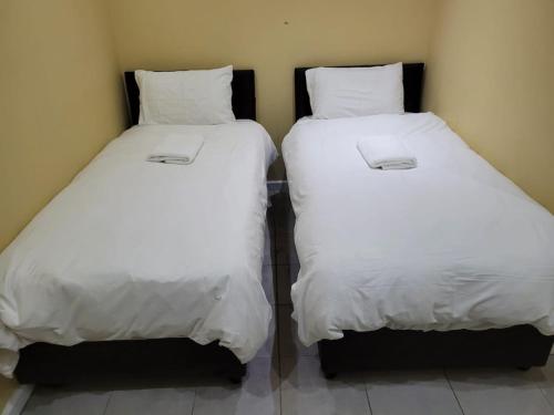 two beds with white sheets sitting next to each other at On the Wrench in Cape Town