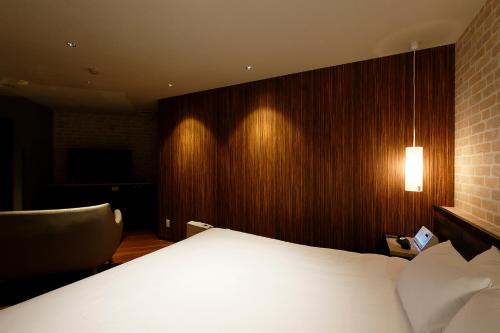 a bedroom with a white bed and a chair at 555 MOTEL GOTEMBA in Gotemba