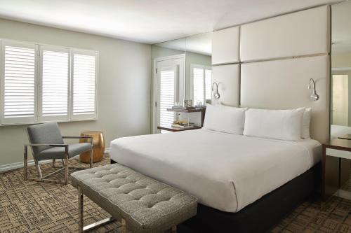 a bedroom with a large white bed and a chair at Hotel Ziggy On Sunset in Los Angeles