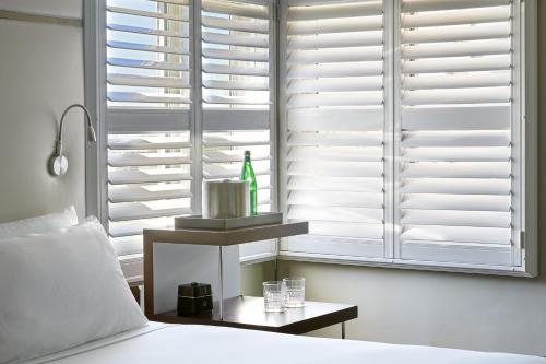 a bedroom with white shuttered windows and a bed at Hotel Ziggy On Sunset in Los Angeles