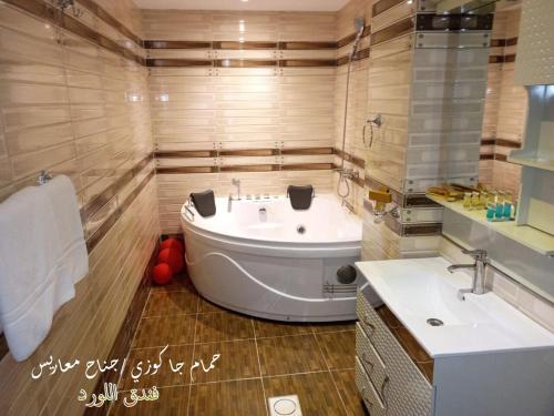 bagno con ampia vasca e lavandino di Al Lord Hotel a Abū Qa‘ar