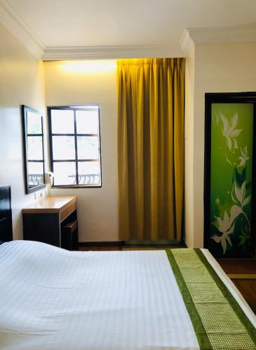 a bedroom with a bed and a desk and a window at Hotel Chua Gin in Cameron Highlands