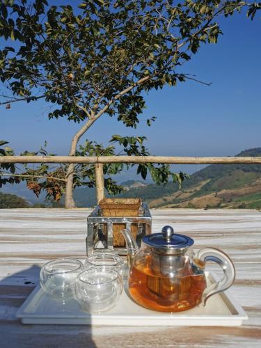 a tea kettle on a tray with glasses on a table at Ban Chomdoi Resort PhaTang in Ban Pha Tang