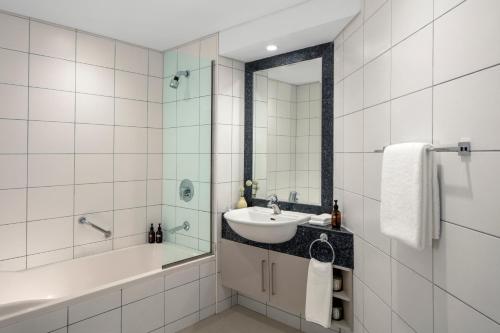 a white bathroom with a sink and a tub and a mirror at Staybridge Suites Dubai Financial Centre by IHG in Dubai