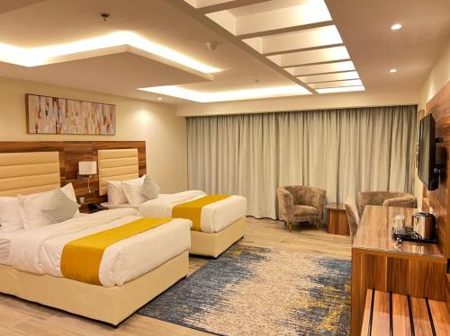 ジッダにあるMoments Hotelのベッド2台とテレビが備わるホテルルームです。