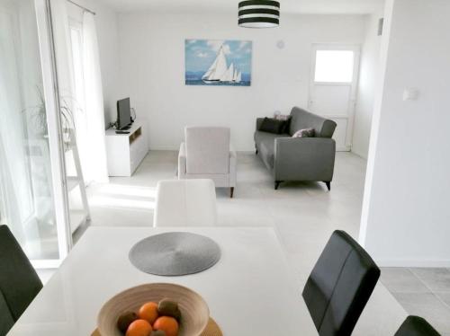 una sala de estar blanca con mesa y sillas en Holiday home Dragi - right next to the beach en Žirje