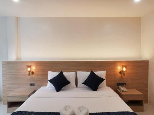a bedroom with a large white bed with black pillows at Nana Beach Hotel & Resort in Pathiu