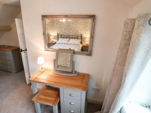 een slaapkamer met een bed en een bureau met een spiegel bij Christmas Cottage in Alfreton