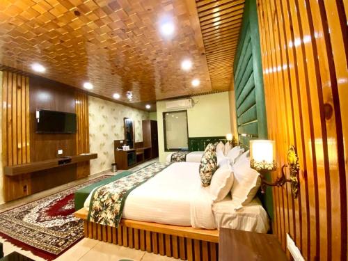 a bedroom with a bed and a flat screen tv at Hotel Woodville Inn - Hotel in Mcleodganj in McLeod Ganj