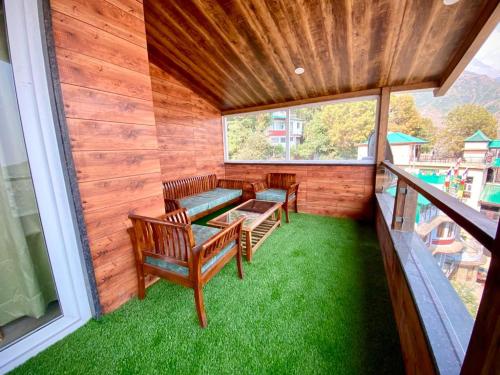 a screened in porch with benches and grass at Hotel Woodville Inn - Hotel in Mcleodganj in McLeod Ganj