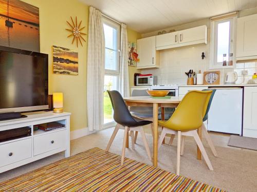 a kitchen with a table and two chairs and a television at 6 Avocet Quay, Emsworth in Emsworth