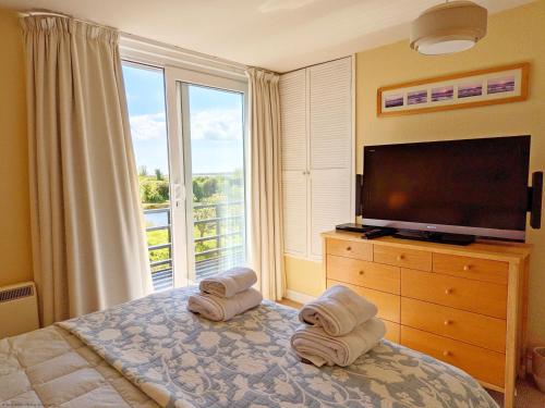 a bedroom with a television and towels on a bed at 6 Avocet Quay, Emsworth in Emsworth