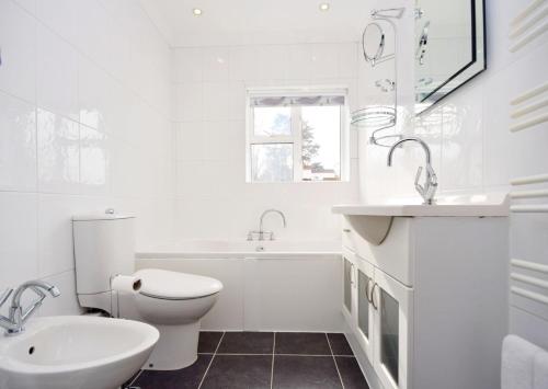 a white bathroom with a sink and a toilet at Bankside, Middleton in Middleton-on-Sea