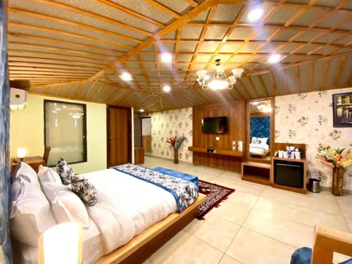 a large bedroom with a large bed and a television at Hotel Woodville Inn - Hotel in Mcleodganj in McLeod Ganj