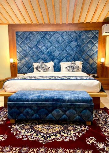a bedroom with a large bed with a blue headboard at Hotel Woodville Inn - Hotel in Mcleodganj in McLeod Ganj