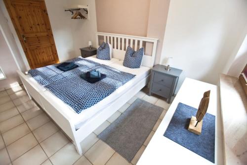 a bedroom with a white bed with blue pillows at Ferienwohnung am Schwimmbachtal in Georgenthal