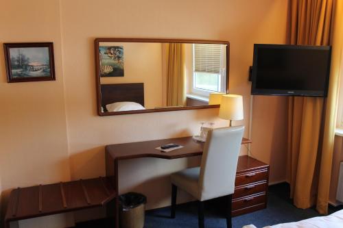 a hotel room with a desk and a mirror at Wiking Hotel in Henstedt-Ulzburg