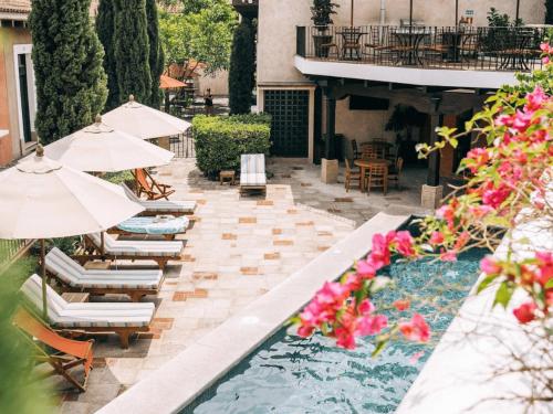 a patio with chairs and umbrellas and a swimming pool at Villa Santa Inés in Antigua Guatemala