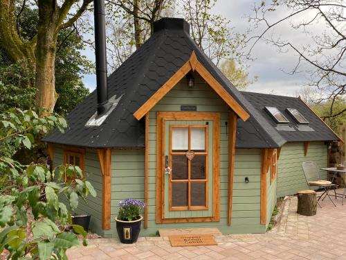a small green house with a black roof at 1-Bed Cabin 2 Adults Outdoor Bath & Wood Burner in Carluke