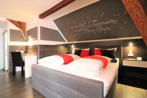 a bedroom with a large bed with red and white pillows at MY HOME Hotel Lamm Rottweil "Smart Home" in Rottweil