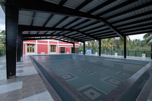 ein leerer Pool mit einem roten Gebäude im Hintergrund in der Unterkunft The Croft Resort - Premium Farm Stay in Thoothukudi