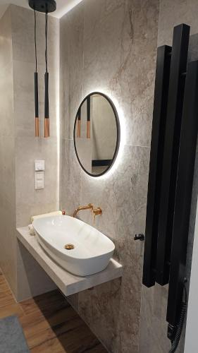 a bathroom with a white sink and a mirror at Kima Apartament Bażantów 40 in Katowice