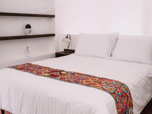 a bedroom with a white bed with a colorful blanket on it at Villa Isabella in Antigua Guatemala