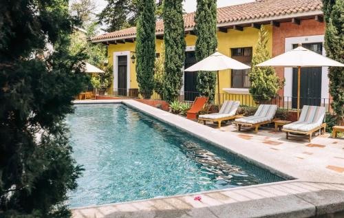 a swimming pool with chairs and umbrellas next to a house at Villa Detalles in Antigua Guatemala
