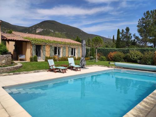 - une piscine avec 2 chaises et une maison dans l'établissement GITE AUX 4 SAISONS DU COLORADO PROVENÇAL - 3 ÉTOILES - Rustrel, à Rustrel