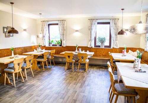 um restaurante com mesas e cadeiras de madeira e janelas em Gasthof Ruckriegel em Seybothenreuth