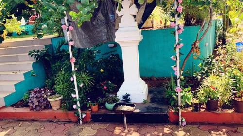 a garden with potted plants and a white column at Stan-Inn, North Goa, Vagator, with strong WIFI,free private parking & kitchen, Can Cook where you stay in Vagator