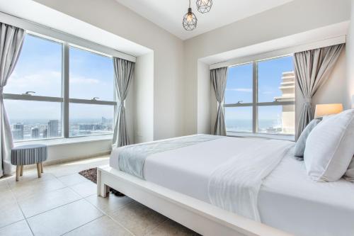 1 dormitorio con cama blanca y ventanas grandes en Icon Casa Living - Elite Residence Tower, en Dubái