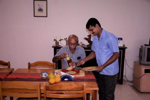 Dois homens à volta de uma mesa com um prato de comida. em Taura Comfort em Bangalore