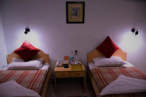 a room with two beds and a nightstand between them at Taura Comfort in Bangalore