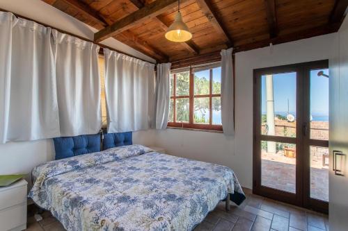 a bedroom with a bed in a room with windows at Fortino's Hause in Porto Santo Stefano