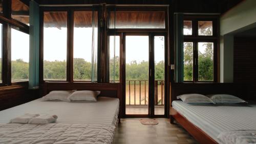 two beds in a room with windows and a balcony at Homestay Dat Viet in Tân Phú