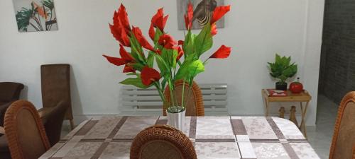 stół z wazonem czerwonych kwiatów w obiekcie La Wans reposante F3 w mieście Saint-Pierre