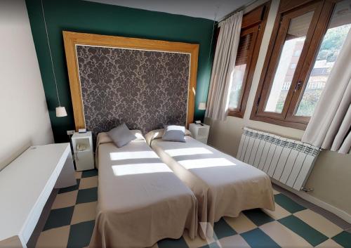two beds in a room with green walls and windows at La Castellana - Habitaciones y desayuno in Benasal