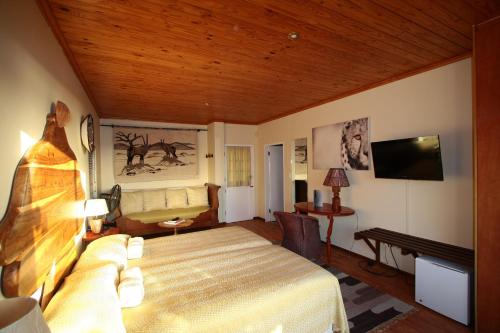 a bedroom with a bed and a couch and a television at Lagoon Lodge in Walvis Bay