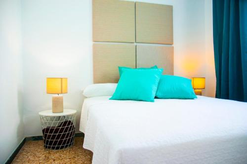 une chambre avec un grand lit blanc avec des oreillers bleus dans l'établissement Arena y el Mar, à Famara