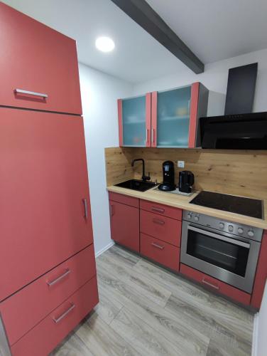 cocina con armarios rojos y fogones en Wunderschöne Ferienwohnung en Lengfurt