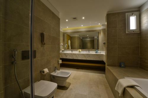 a bathroom with a toilet and a sink and a mirror at Sealine Beach, a Murwab Resort in Mesaieed