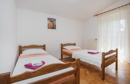 two beds in a room with white walls and wooden floors at Plava Adria Podstrana in Podstrana