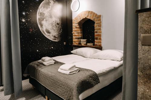 a bedroom with a bed with a moon mural on the wall at Apartamenty K2 Podmurna 36 in Toruń