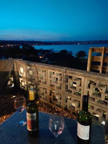 two bottles of wine sitting on a table with wine glasses at Fishermen's cottage with log burner, 2 bathrooms & sea views from garden terraces in The Mumbles