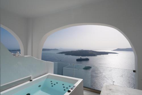 a white bathroom with a view of the ocean at Asha Luxury Suites in Fira