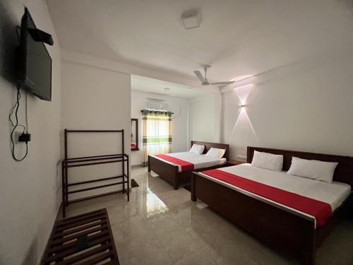 a room with two beds and a television in it at Nugasewana Guest in Anuradhapura