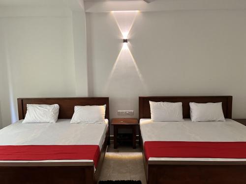 two beds in a room with a light on the wall at Nugasewana Guest in Anuradhapura